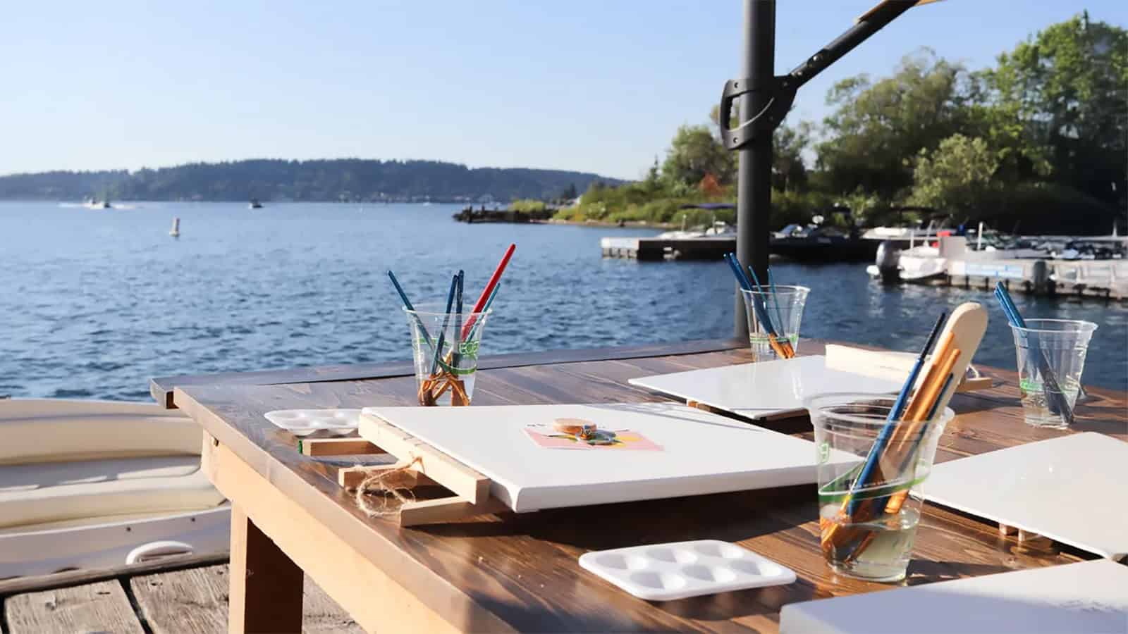 Under the clear sky, the setting of outdoor art awaits inspiration, with empty sails and brushes for painting in glasses. A small picture nearby hints at the potential of creativity. Perfect for an apartment has escaped from this day on Valentine's Day, trees and boat grace in the background of the calm lake.