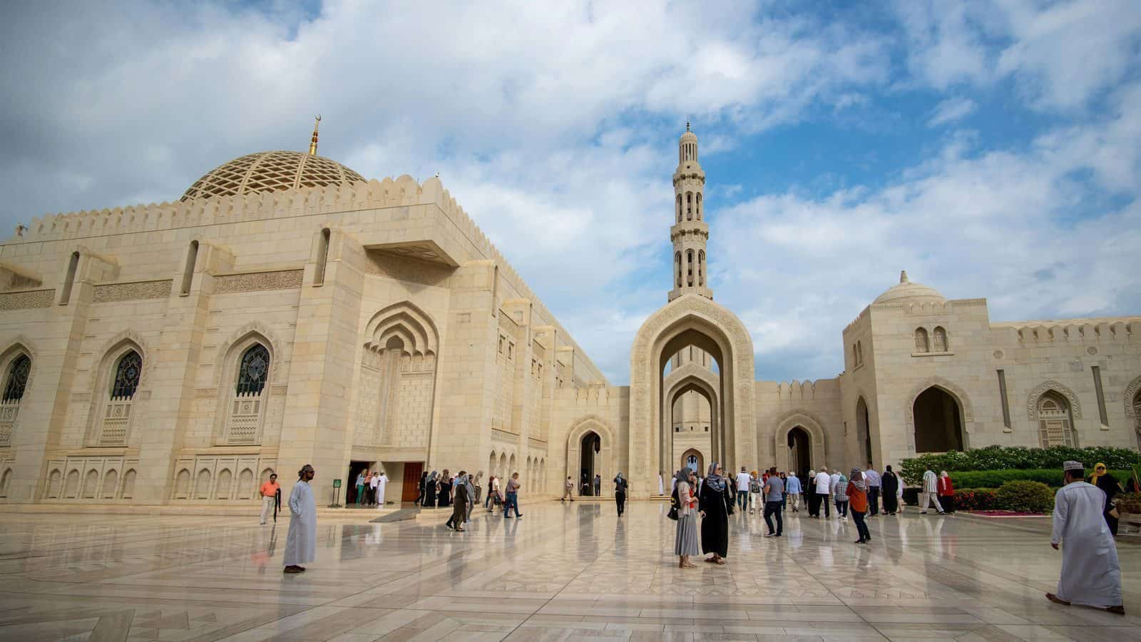 Travelers from Seattle in 2025 gather outside a large mosque with intricate architecture, domes, and a tall minaret under a partly cloudy sky, marking it as one of the ten top travel destinations.