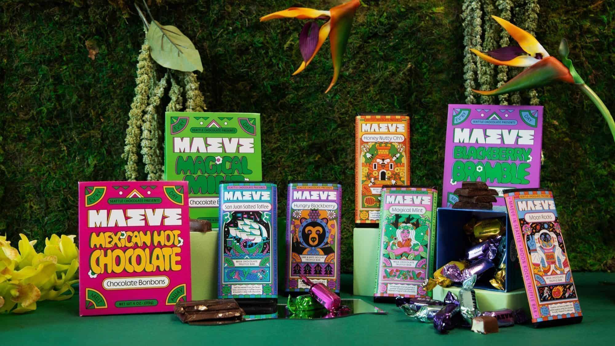 Seattle Chocolate rebrands to Maeve, offering assorted chocolate bonbon boxes with vibrant packaging on a green surface. Wrapped candies and decorative plants in the background enhance this delightful, visual treat.