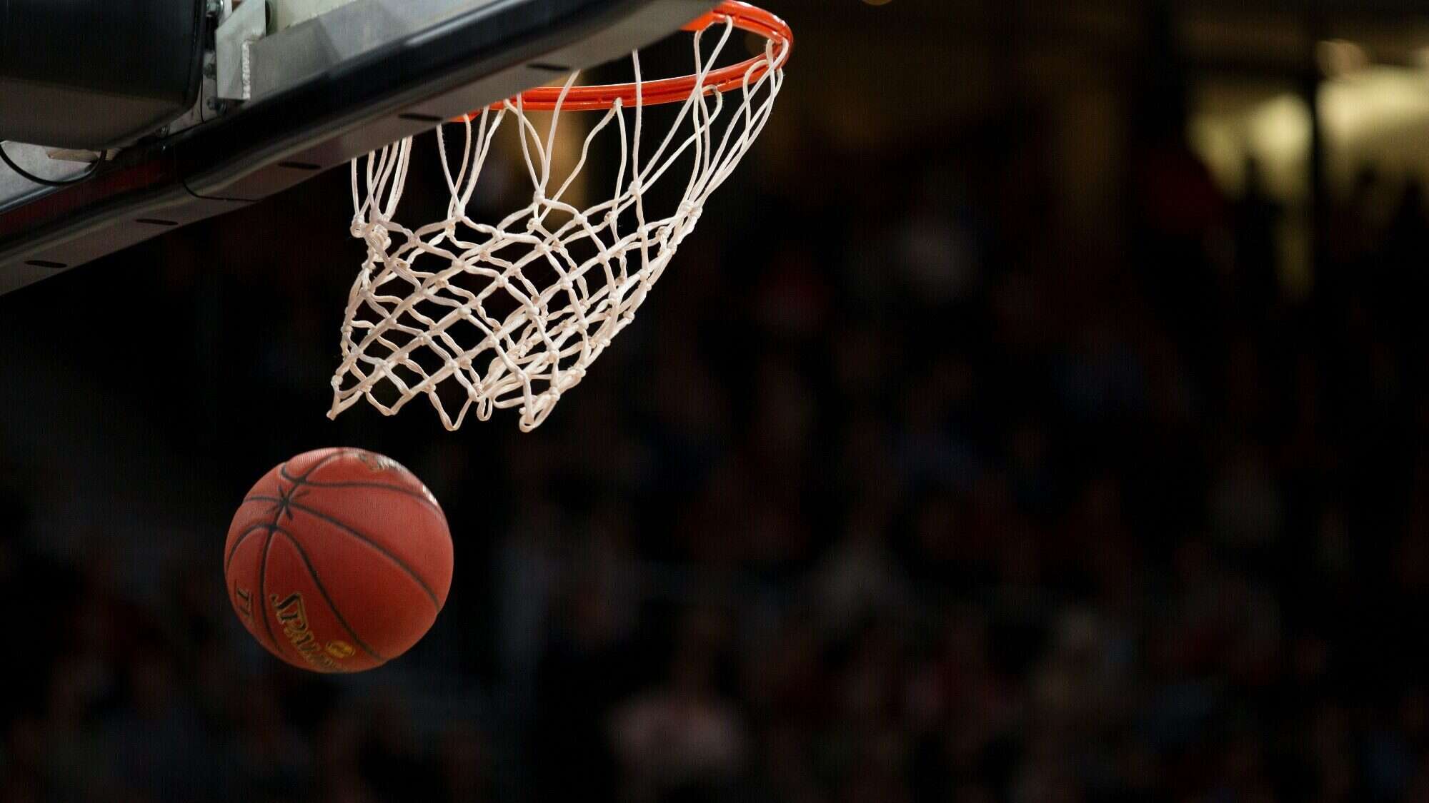 markus-spiske-BfphcCvhl6E-unsplash-16-9-2000x1125 During March Madness, a basketball arcs towards the hoop, with an electrified crowd visible in the background.