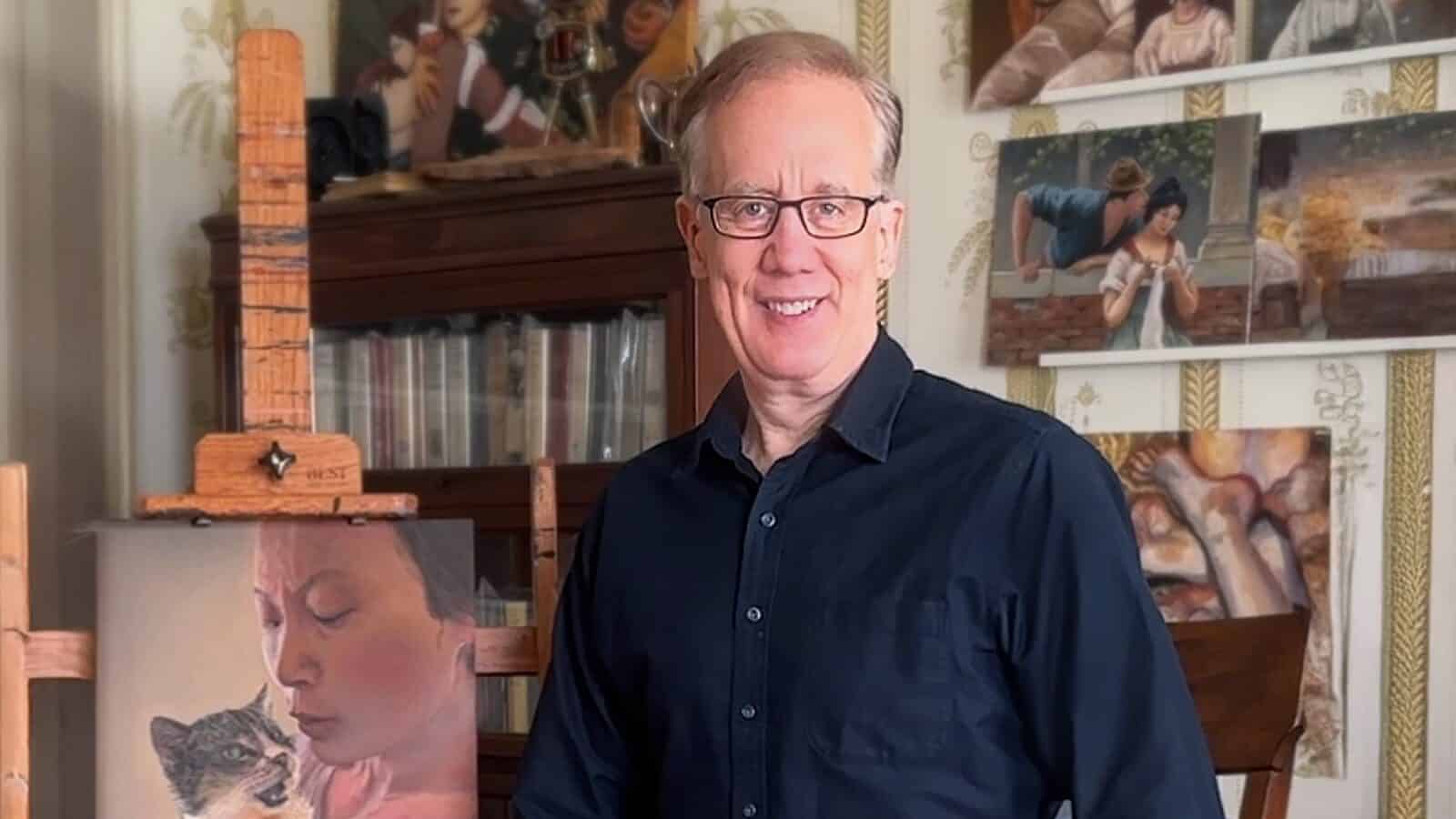 AndrewConru-April2025_1600x900 Former tech entrepreneur Andrew Conru stands smiling in an art studio, wearing glasses and a dark shirt. Behind him are various paintings and a bookshelf, with an easel displaying a portrait of a person with a cat. Conru recently announced the Seattle Prize Masters Fellowship.