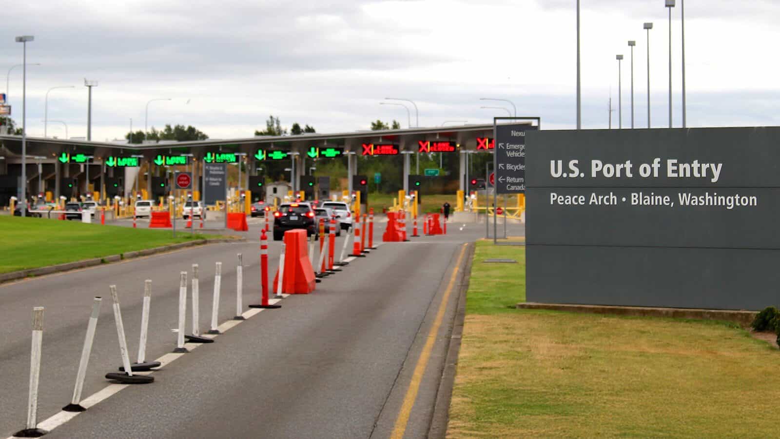 PortOfEntryBlaine_DavidFulmer-Flickr_1600x900 Cars approach the U.S. Port of Entry at Peace Arch in Blaine, Washington, as Whatcom County grapples with plummeting tourism; traffic cones guide vehicles and a large sign indicates the border crossing near Bellingham.