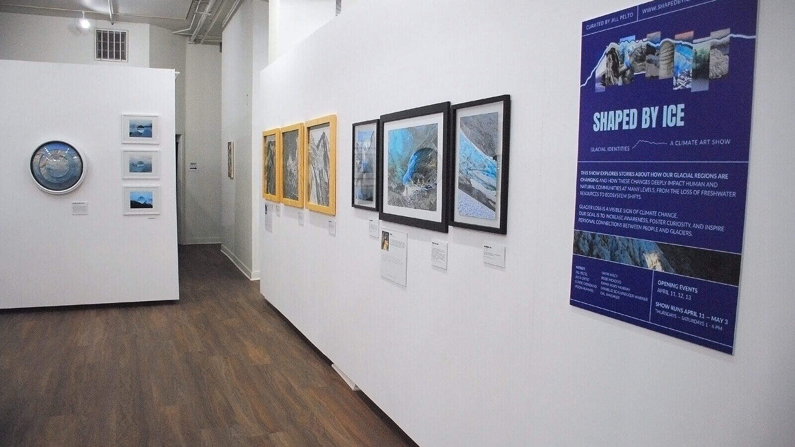 A gallery wall displays framed art and photography, with a large informational poster titled "Shaped by Ice" on the right side, highlighting Glacial Expressions. The floor is wooden.