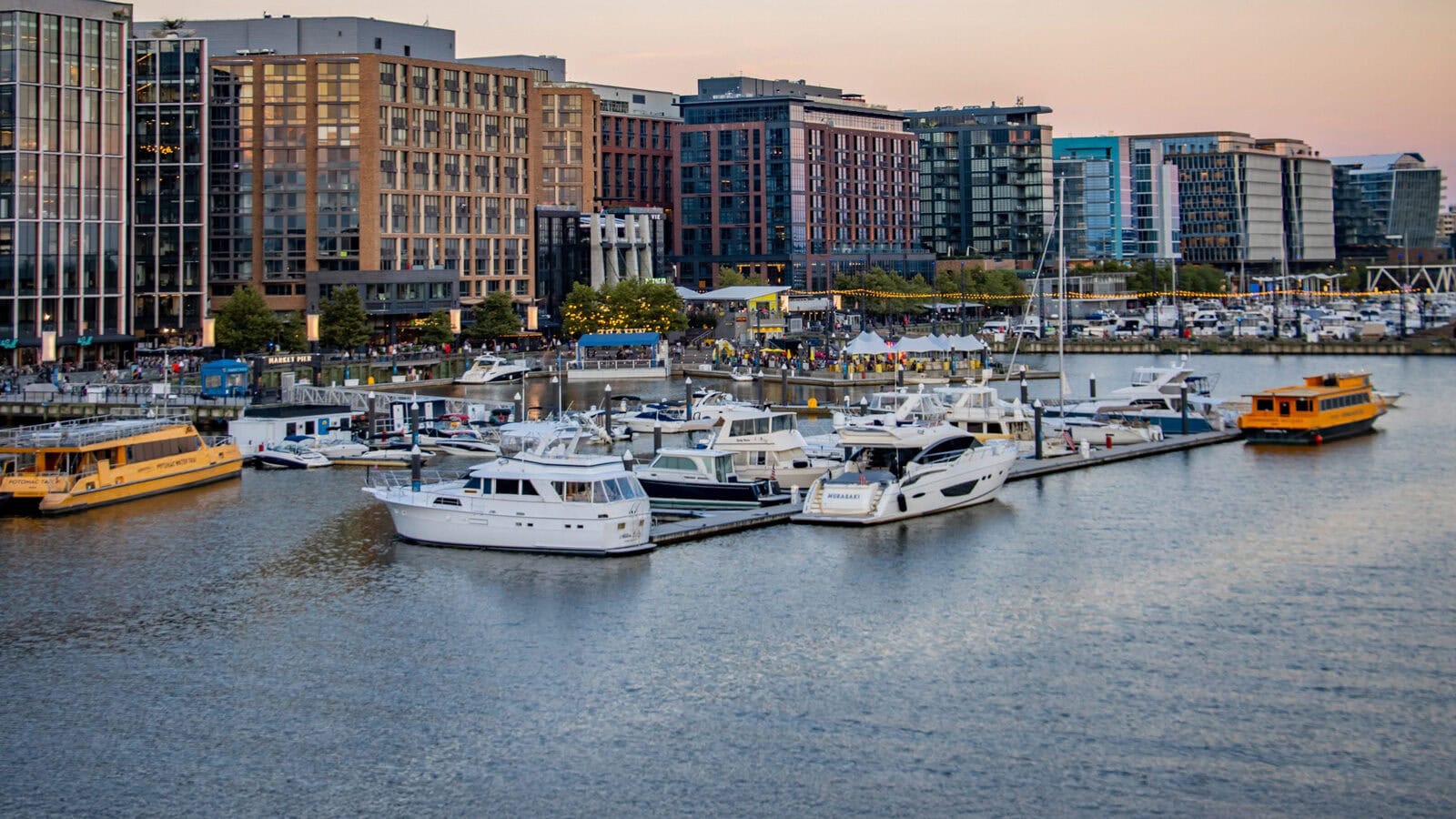 Marina with several docked yachts and boats in front of modern waterfront buildings at sunset, capturing the essence of A Stroll Through Old & New D.C.
