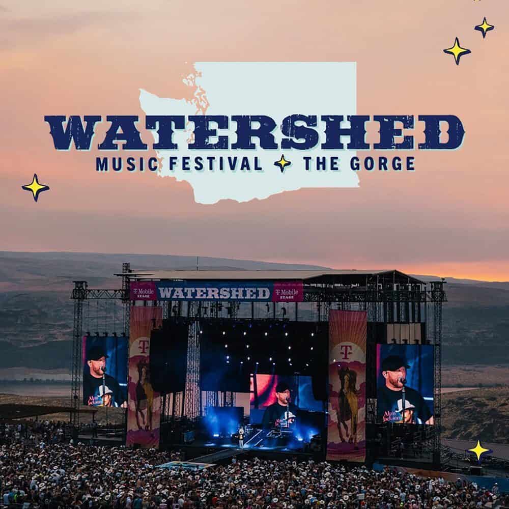 Outdoor stage at Watershed Music Festival at The Gorge—a Must List experience on 07-31-2025—with a large crowd, sunset sky, mountains in the background, and the festival logo displayed above.
