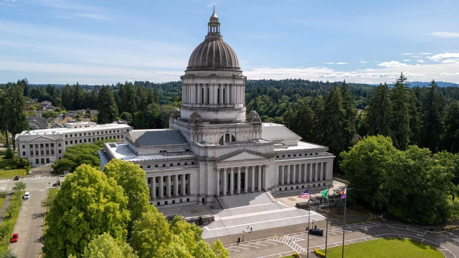 Aerial view of the Washington State Capitol building surrounded by trees under a clear sky.