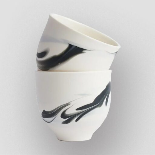 Two white ceramic bowls with black abstract swirl patterns are stacked on a plain light gray background—a modern choice for unique gift ideas.