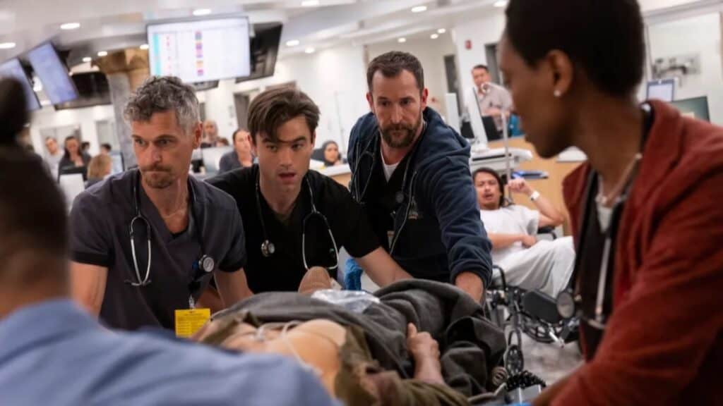 A group of healthcare professionals urgently treat a patient on a stretcher in a busy hospital emergency room.