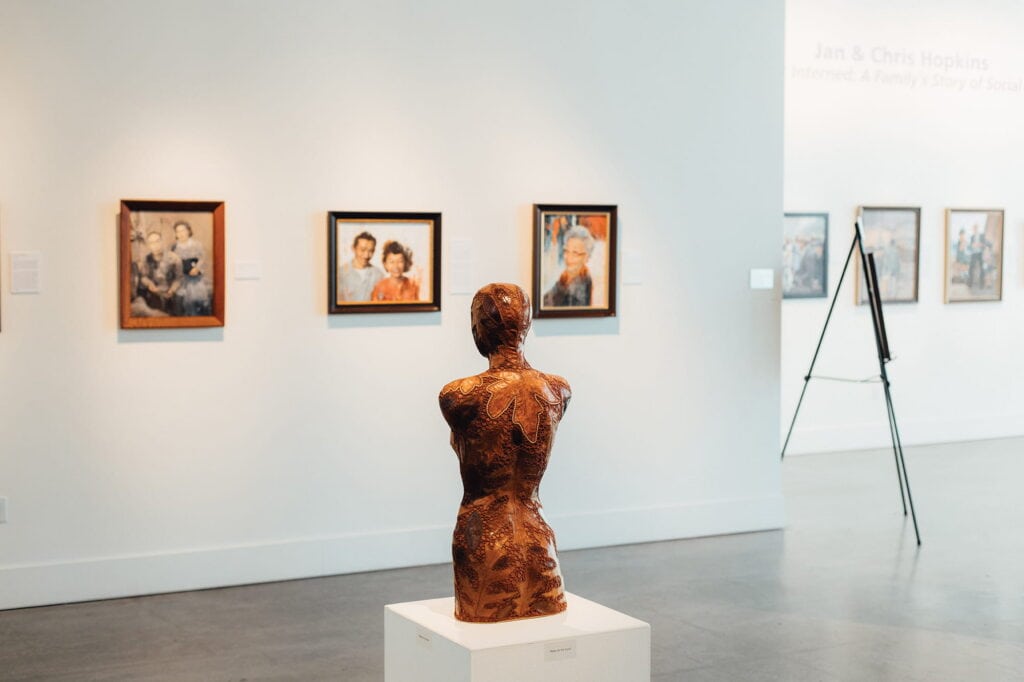 A sculpture of a torso is displayed on a pedestal in an Everett art gallery, with framed portraits hanging on the white walls in the background—highlighting why it's among the Best Places to Live for art lovers.