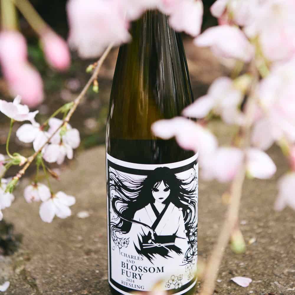 A wine bottle labeled "Blossom Fury Riesling" with an illustration of a woman in black and white, surrounded by cherry blossom branches.