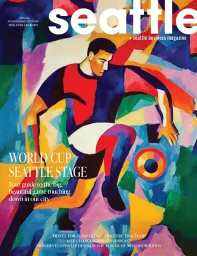 Abstract painting of a soccer player in action is featured on the cover of Seattle Business Magazine with World Cup and city-related headlines.