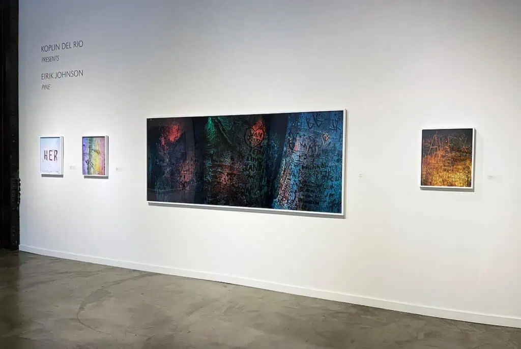 A white gallery wall displays five framed abstract artworks of varying sizes with spotlights above, on a polished concrete floor. Text on the wall reads, "Koplin Del Rio presents Erik Johansson FIVE.