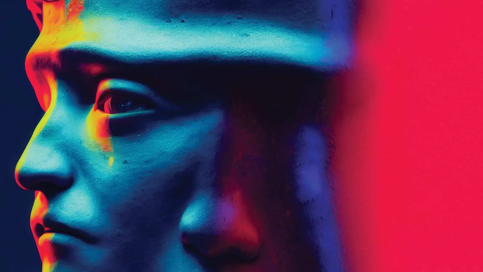 Close-up of a stone statue’s face in blue, yellow, and red lighting with a bright red gradient on the right side of the image, inspired by Seattle health and fitness trends that emphasize bold contrasts and vibrant wellness aesthetics.