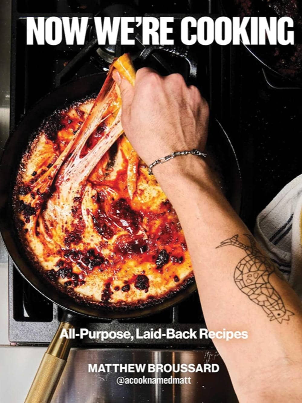 A tattooed hand pulls melted cheese from a skillet of bubbling food on a stove. Text reads: "Now We're Cooking. All-Purpose, Laid-Back Recipes." From Capitol Hill restaurant chef Matthew Broussard's cookbook.