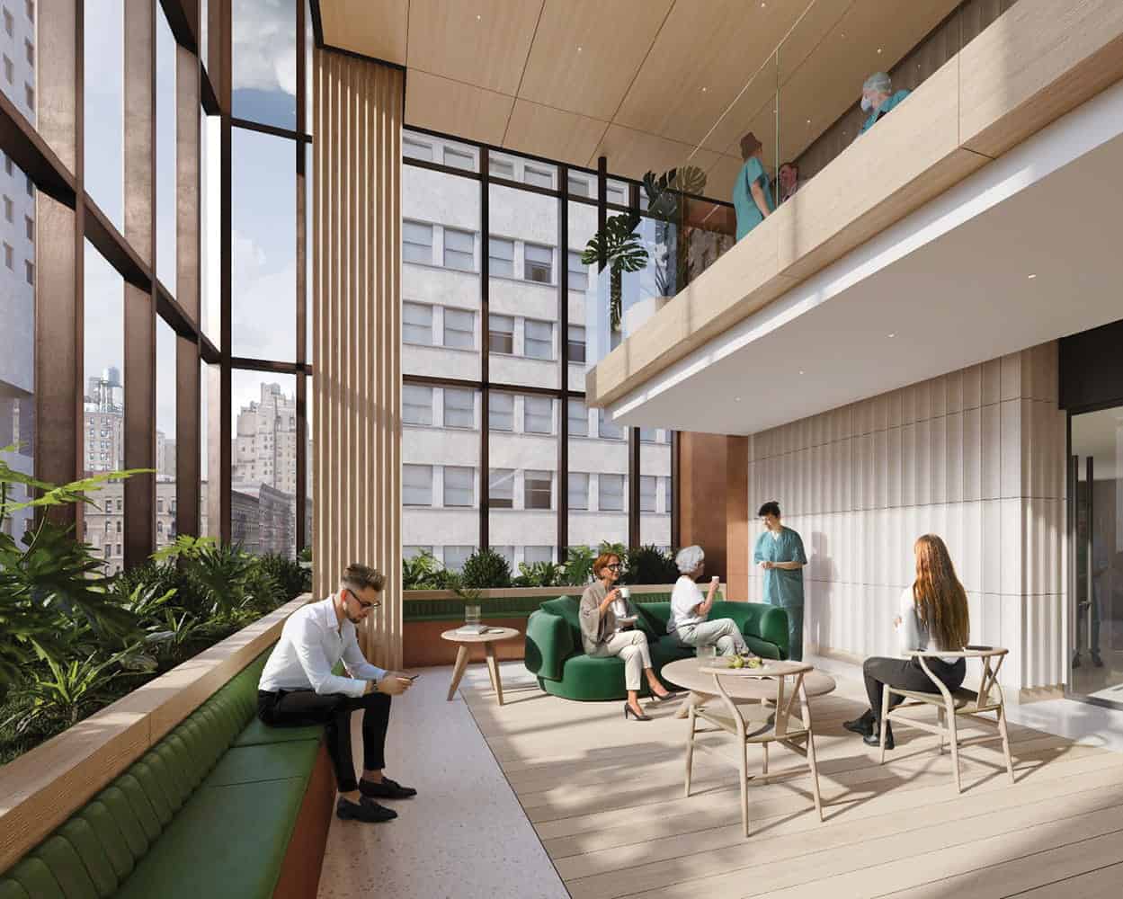 A modern, daylight-filled lounge with green seating, large windows, and people sitting or standing, some talking and others using devices. A few more people are on the upper level. The space reflects principles of biophilic design in healthcare, enhancing comfort and well-being through its connection to nature.