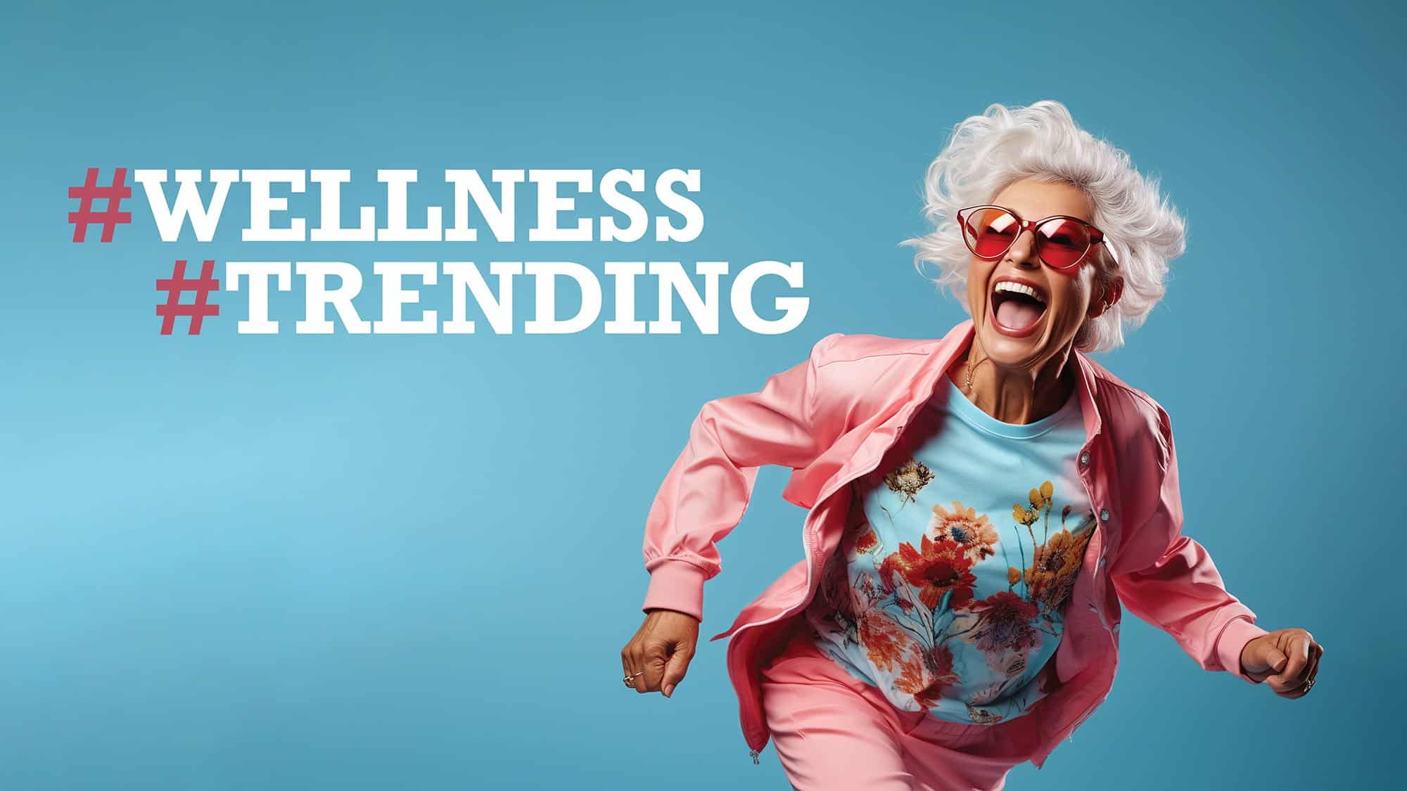 Older woman in pink outfit and sunglasses looks energetic against a blue background, embodying the spirit of popular health trends. Text reads "#WELLNESS #TRENDING" in bold white font on the left side.