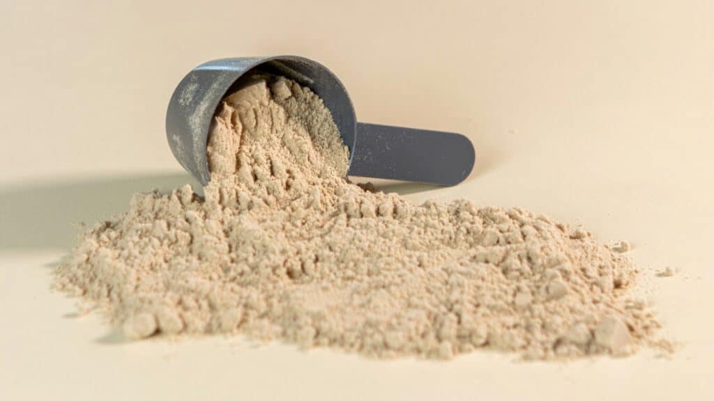 A plastic scoop spills a pile of beige protein powder onto a light surface, reflecting the latest Seattle health and fitness trends that focus on wellness and holistic nutrition.