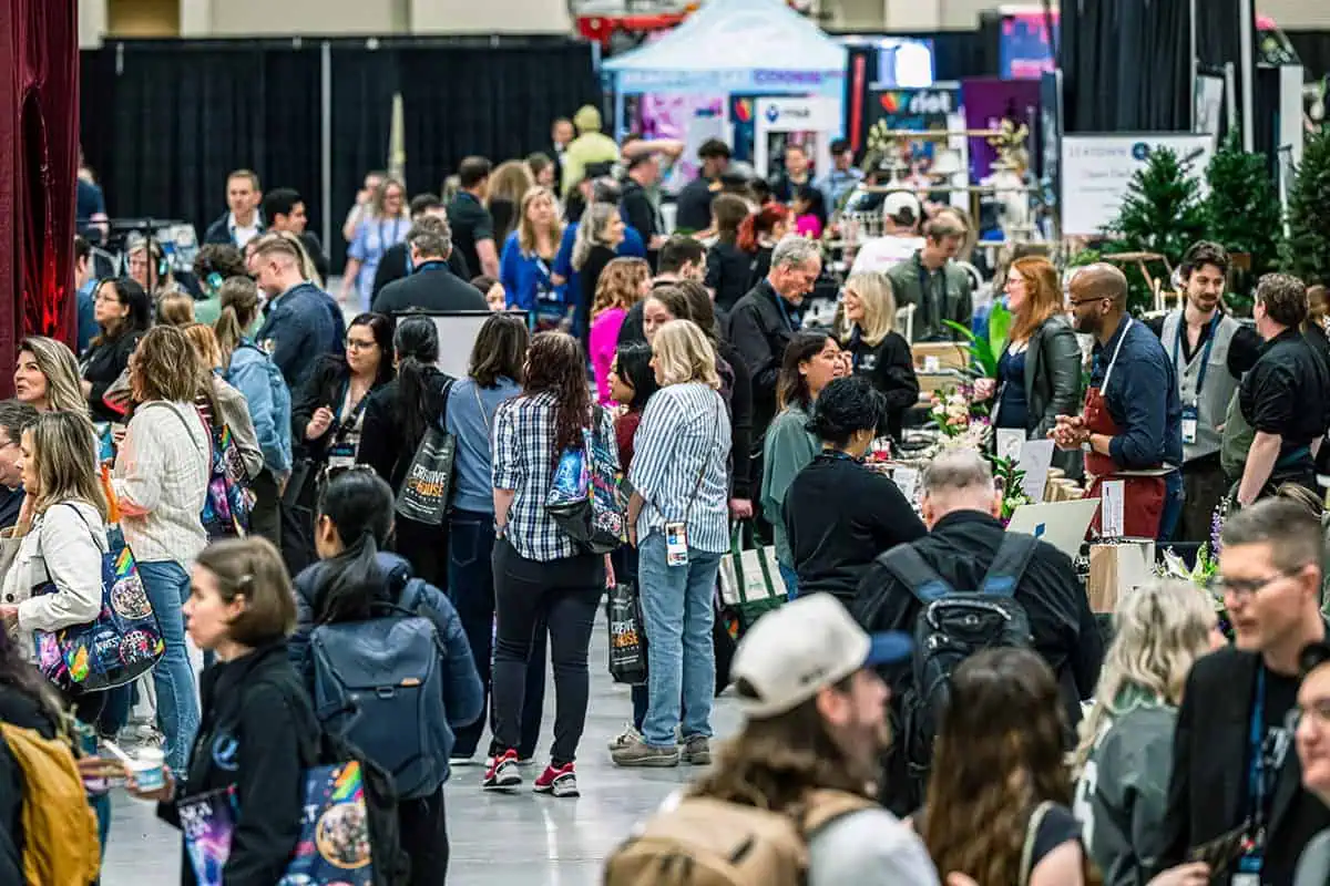 A large crowd of people walks and gathers around vendor booths at the Northwest Event Show, a premier convention and trade show event in Seattle for the hospitality industry.