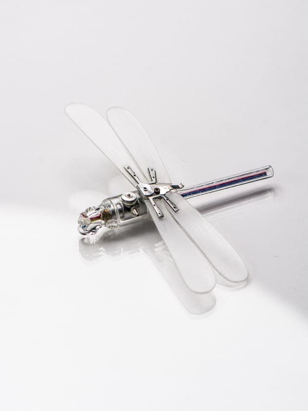 A dragonfly figurine made of clear plastic and mechanical metal parts, often discovered during US art trips.