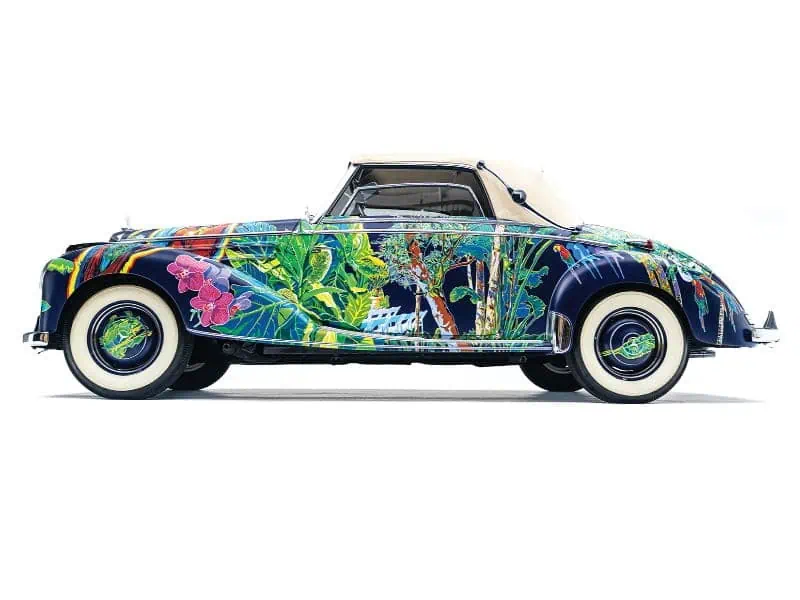A vintage convertible car with a dark blue body painted with colorful tropical flowers, a standout piece for top art collections.