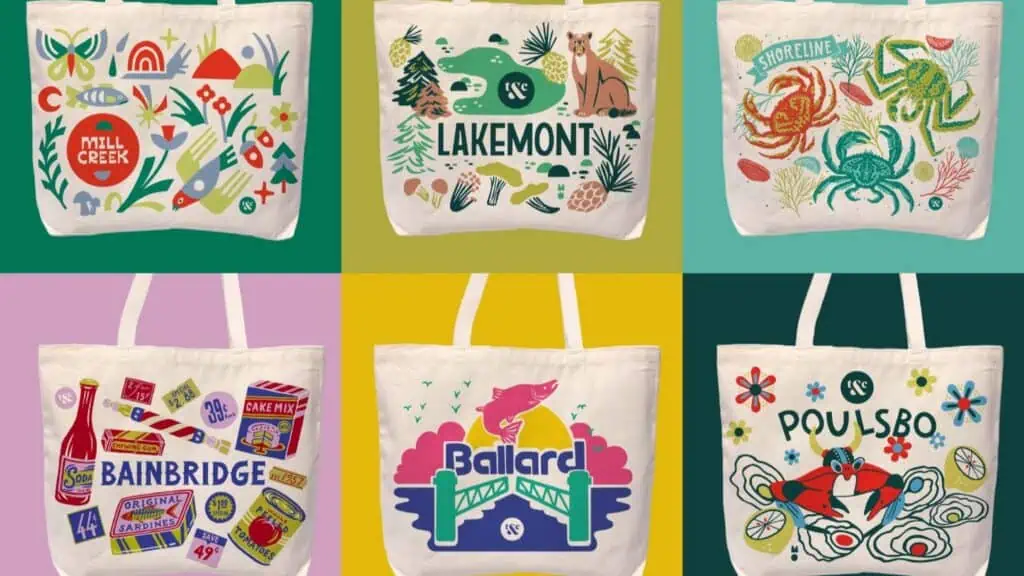 Six illustrated tote bags are displayed, each featuring colorful, stylized designs representing different locations, including Mill Creek, Lakemont, Shoreline, Bainbridge, Ballard, and Poulsbo.