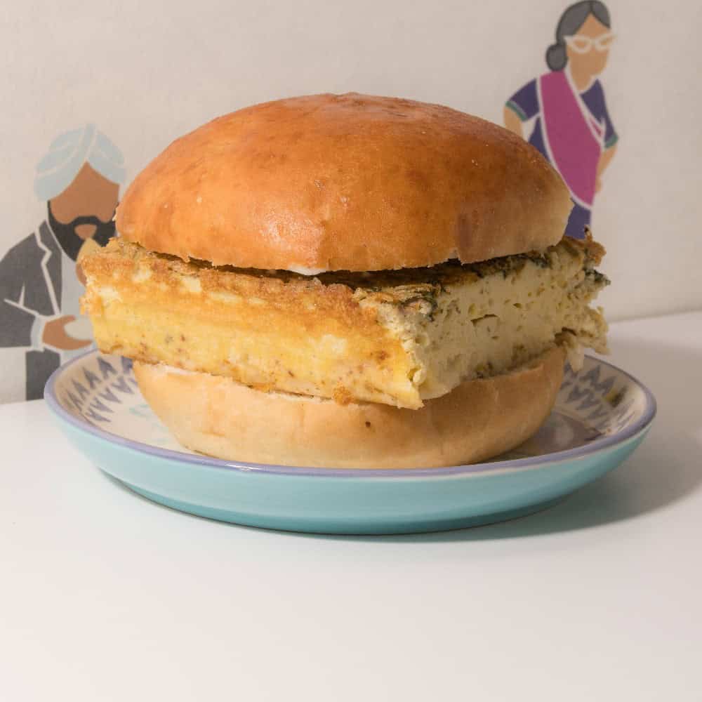 An egg patty sandwich on a brioche bun, served on a patterned plate.