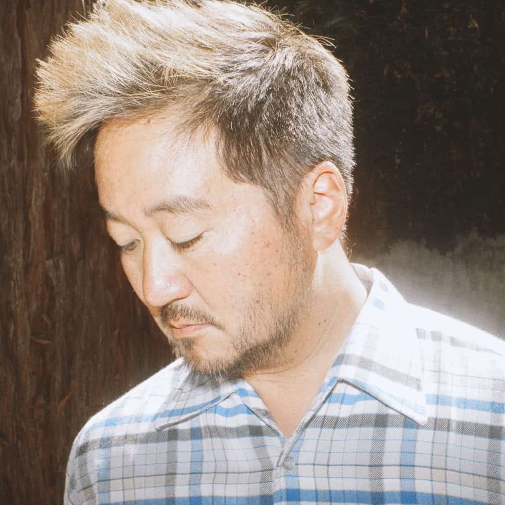 A man in a plaid shirt looking downward.