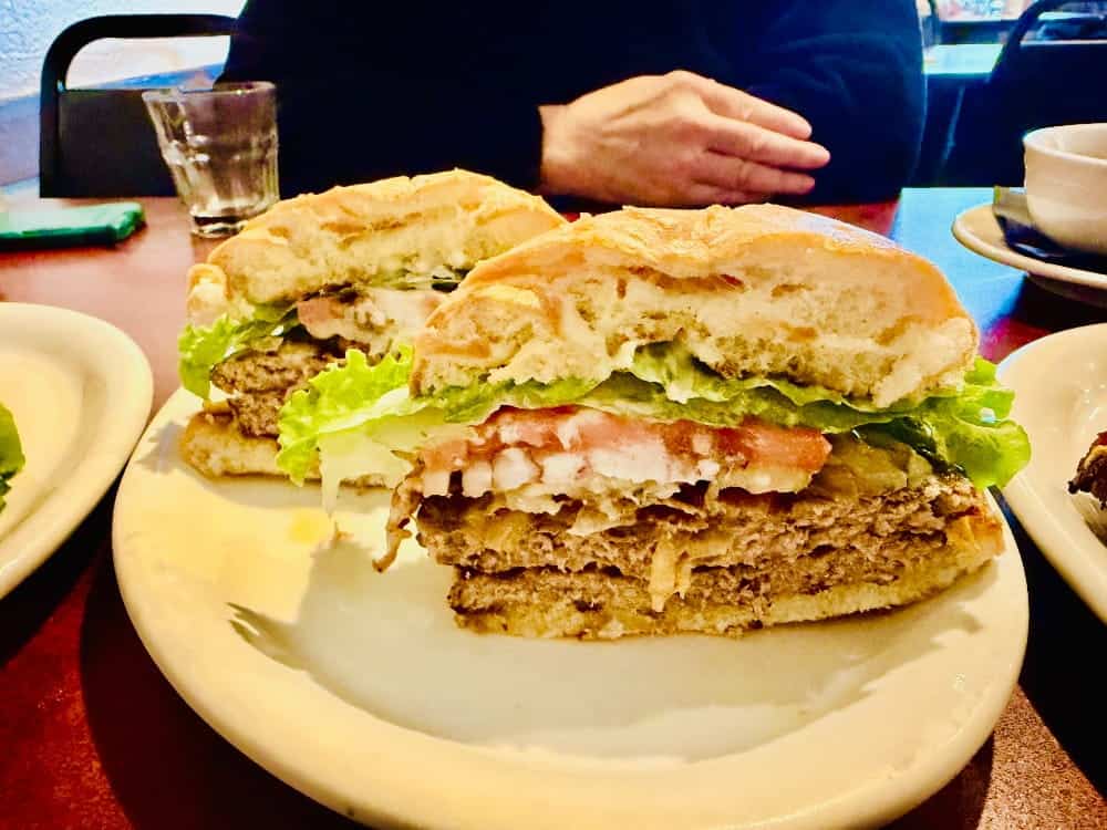 A sliced cheeseburger with lettuce, tomato, and onion on a plate, featured in our burger guide.