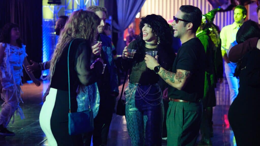 A group of people in costumes talking and holding drinks at a party.