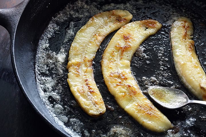 Bananer som steks i en gjutjärnspanna.
