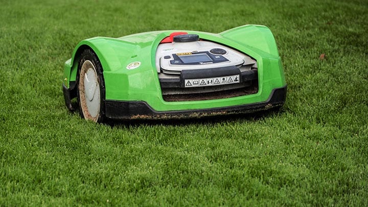 En grön robotgräsklippare som klipper en gräsmatta.