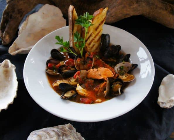 A bowl of clams and mussels with bread on a table.