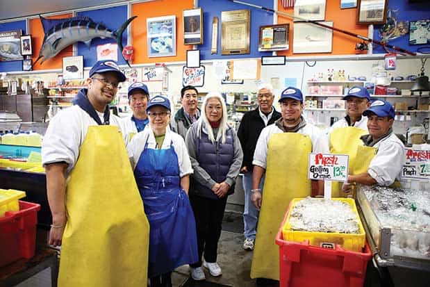 A group of people posing for a photo in a fish market.