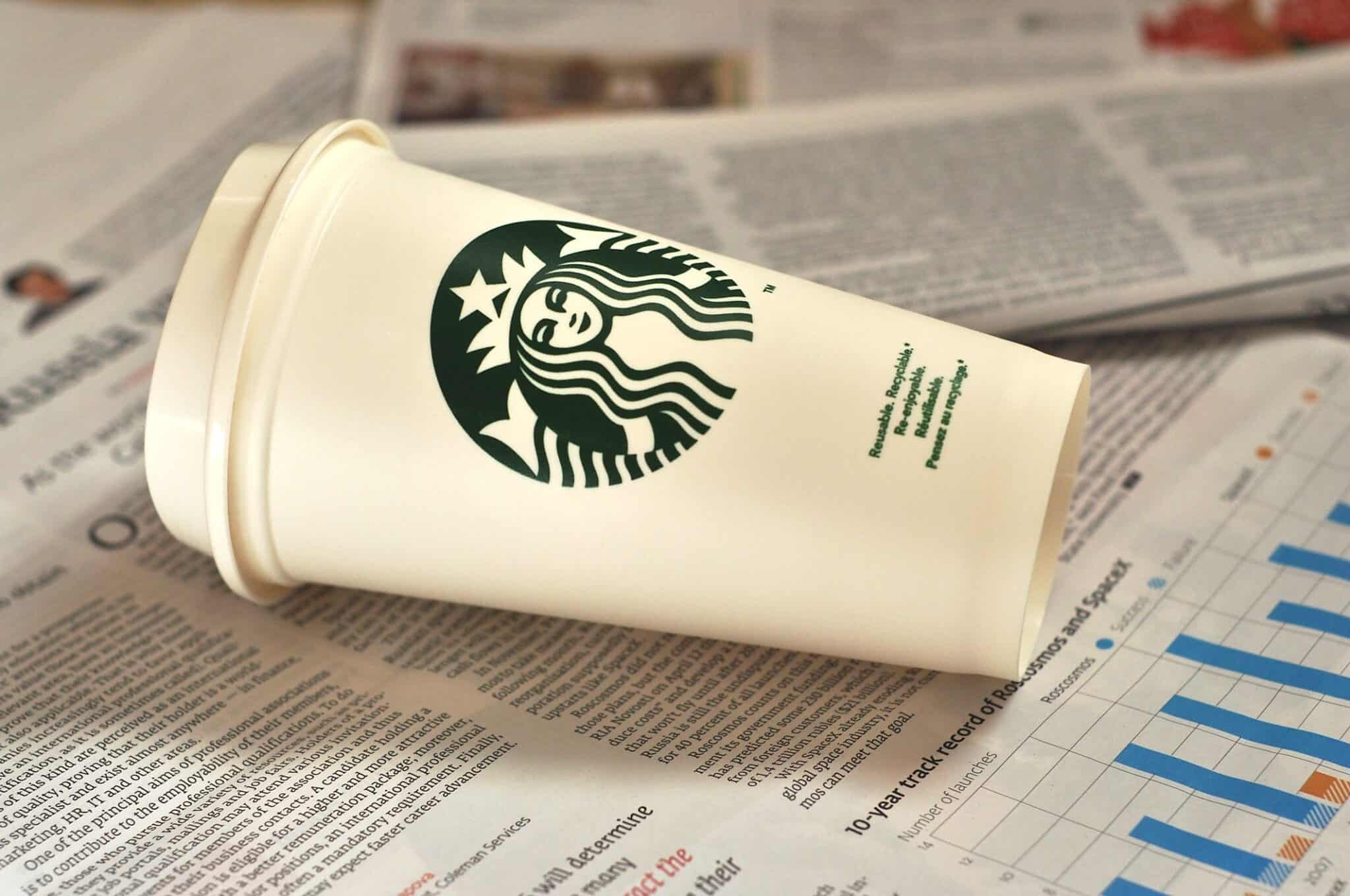Moscow, Russia - April 17, 2016: The empty cup from Starbucks cafe on the table with newspapers at the office