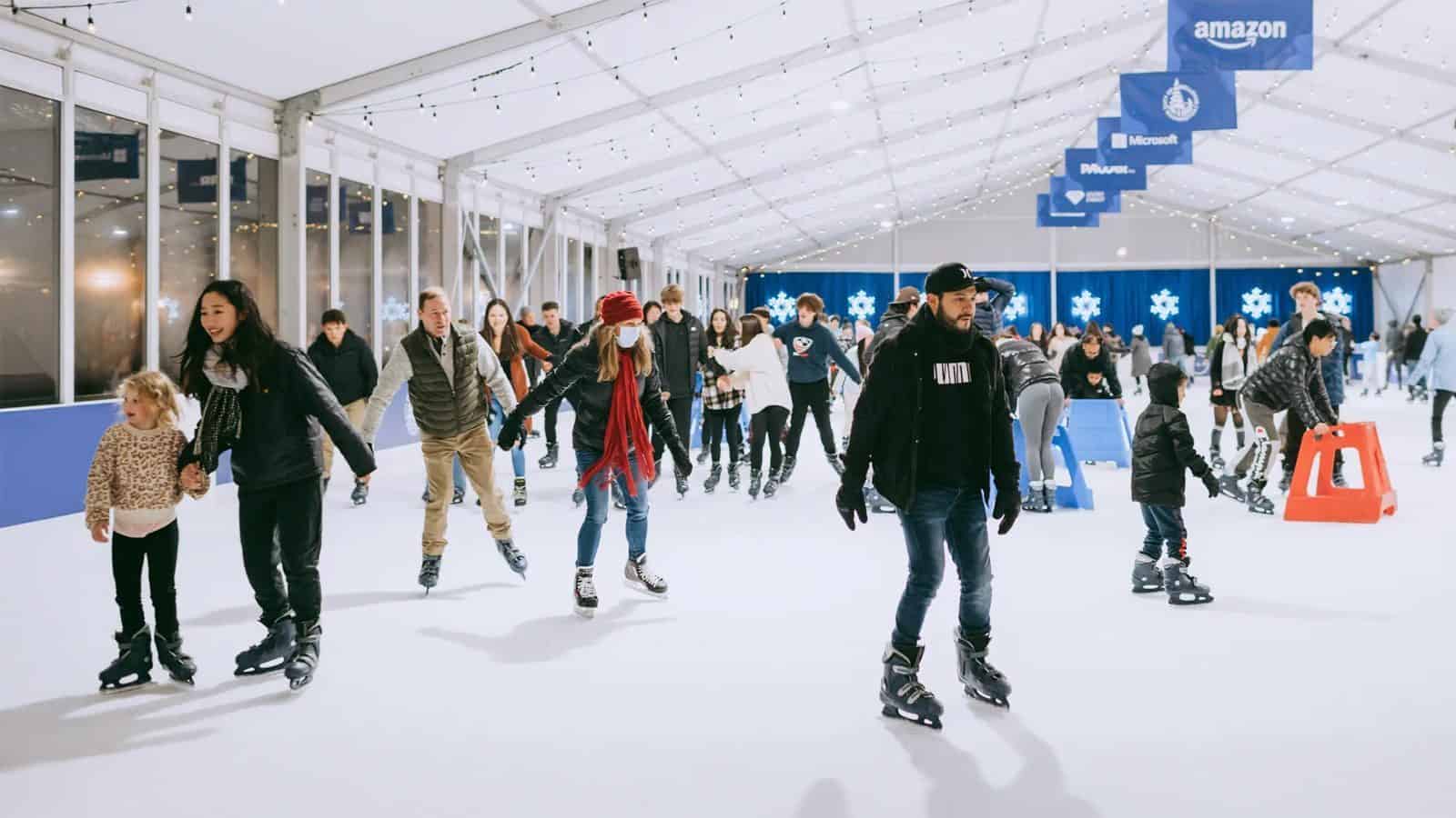 In 2025, people glide gracefully on the ice indoors under a shimmering canopy, surrounded by various company banners. It's an activity that deserves a spot on your Must List for a unique and exhilarating experience.
