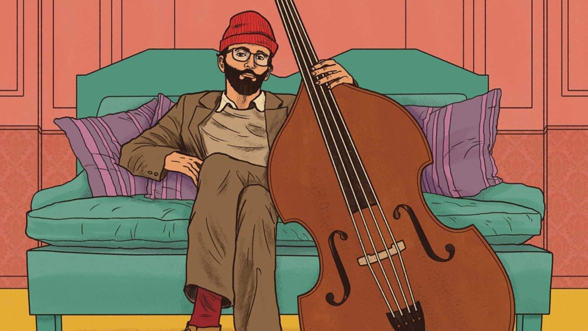 A person wearing a red beanie and glasses sits on a sofa, holding a double bass—a must-list addition for those seeking cozy vibes. The background includes pillows and a wall with paneling, setting the perfect scene for this week's list of things to do.