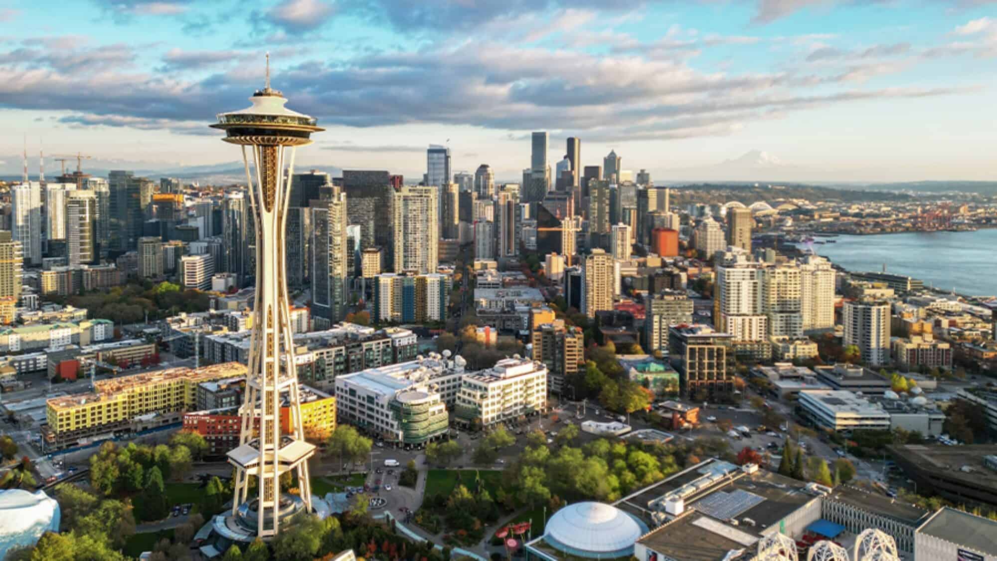 Aerial view of downtown Seattle featuring the Space Needle, city buildings, and a partly cloudy sky.