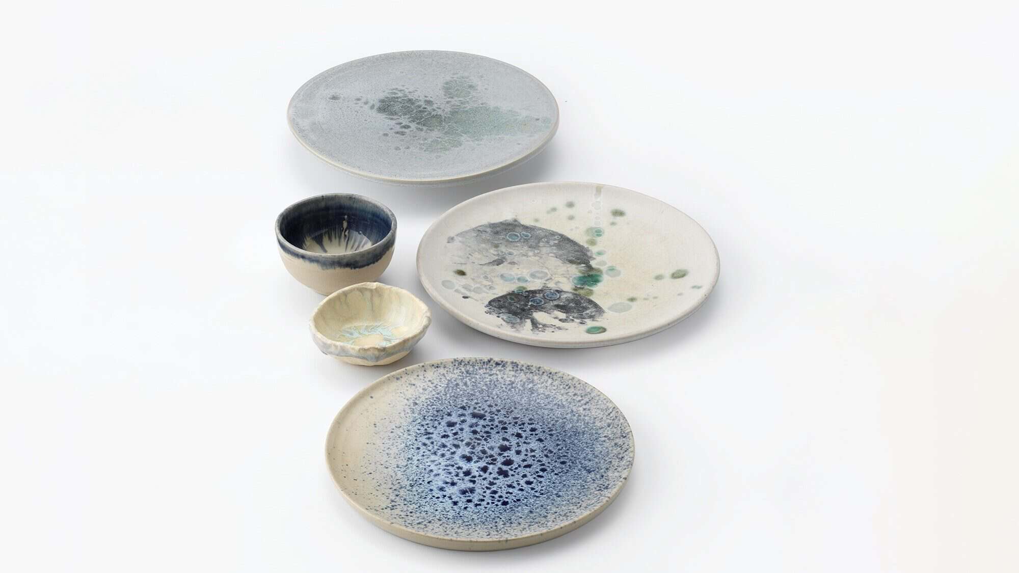 Five ceramic dishes and cups with abstract blue, green, and gray glaze patterns—your Fave Five Little Escapes—arranged on a white background.