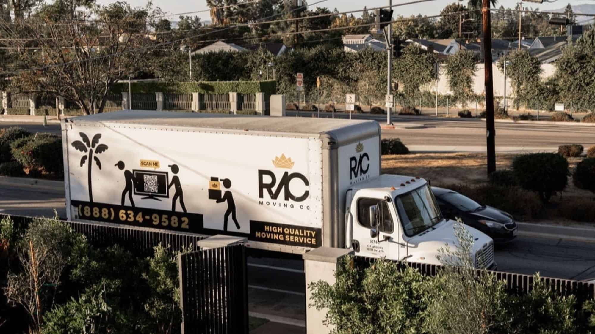 A white moving truck labeled "RAC Moving Co" is parked on a street beside a residential area, perfect for Seattle newcomers settling in, with trees and houses visible in the background.