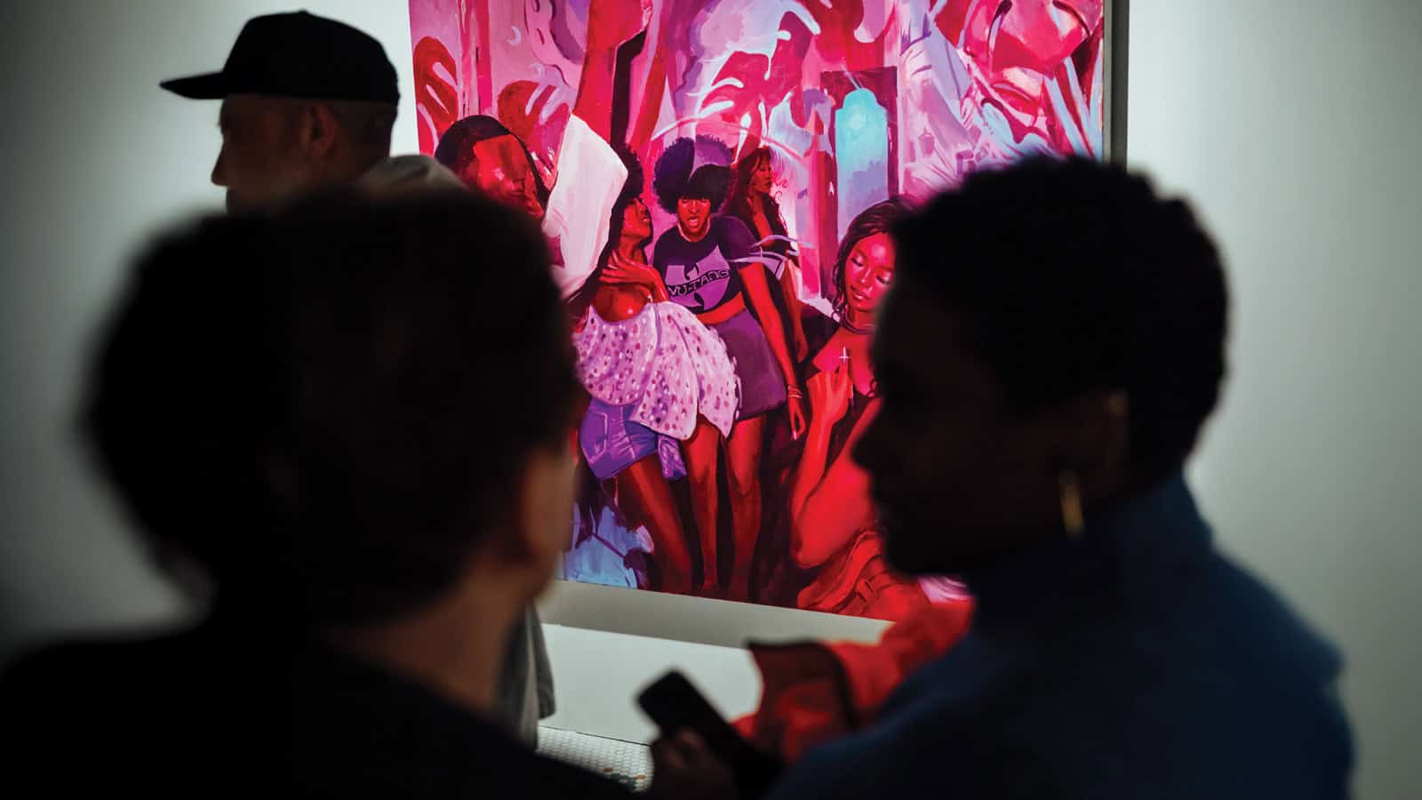 People stand in front of a vibrant, pink-toned painting at Pioneer Square’s space for artists; the foreground figures are in shadow, partially obscuring the artwork at Actualize AiR.