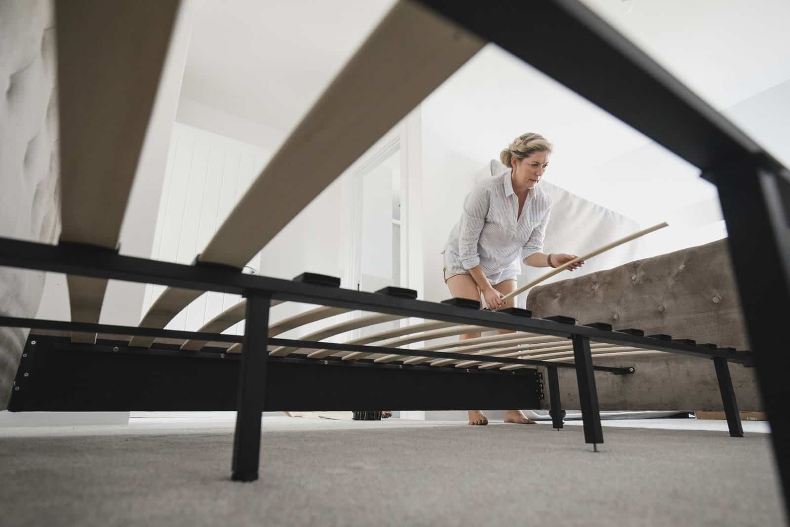 low-angle-view-of-a-mature-woman-setting-up-her-bed-in-her-new-home