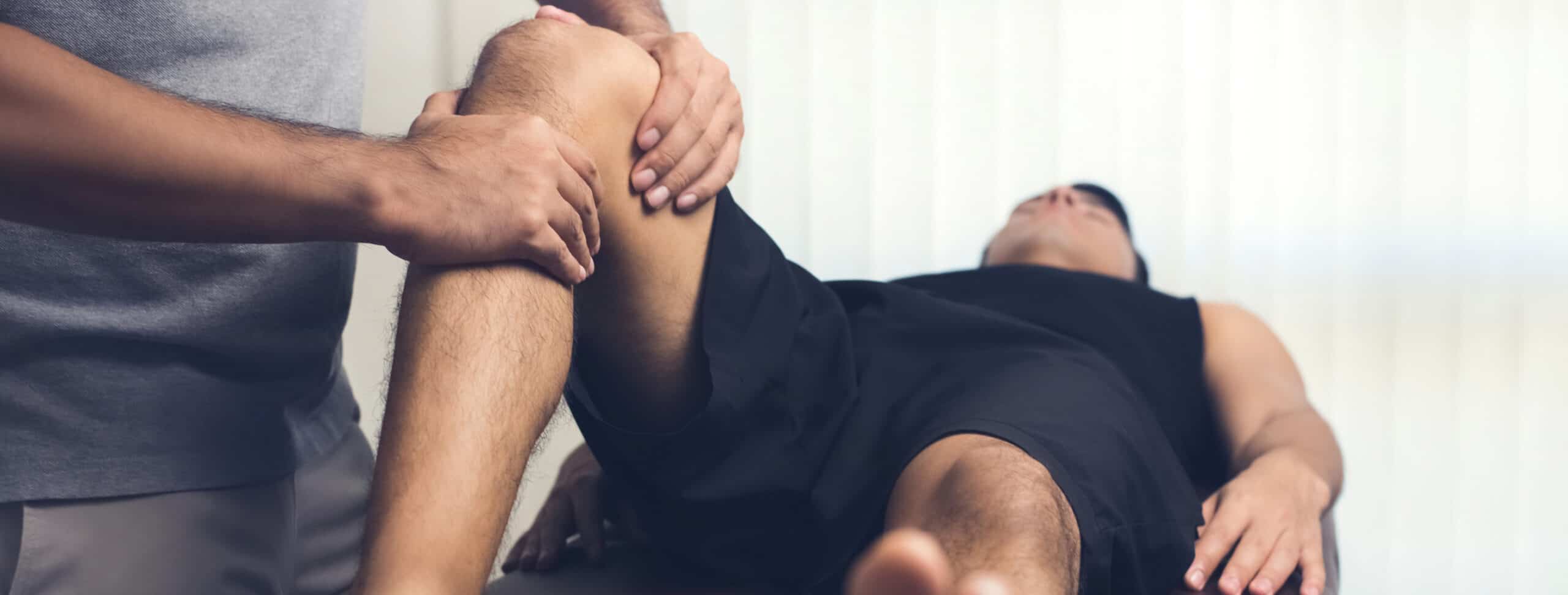 therapist-treating-injured-knee-of-athlete-male-patient-sport-physical-therapy-concept-panoramic-banner