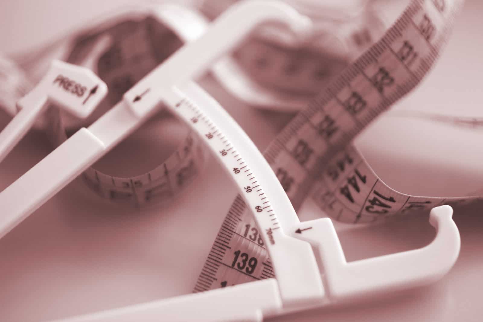 fat-caliper-and-measuring-tape-used-to-measure-waistline-bodyfat-levels-for-fitness-and-obesity-checks