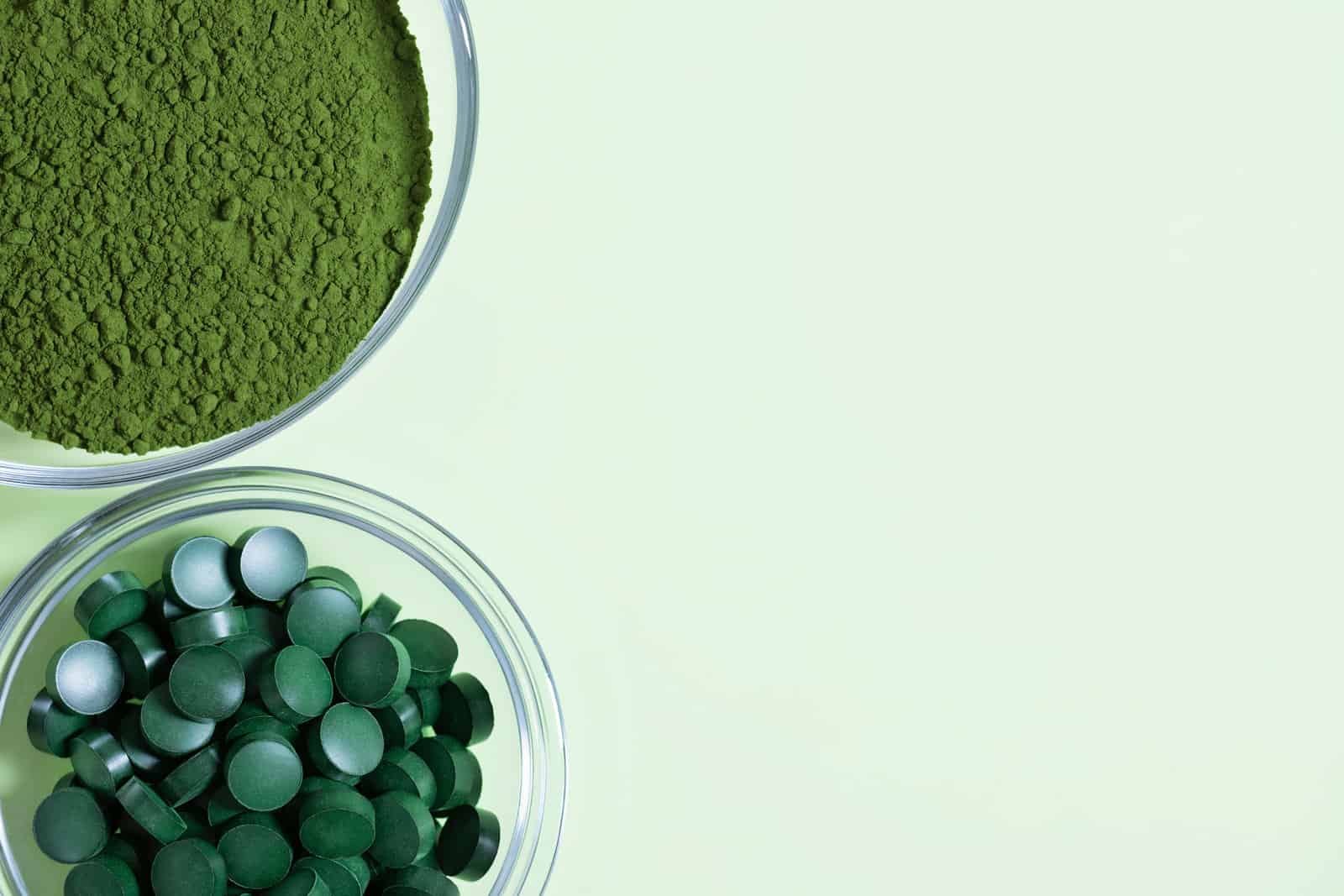 chlorella-powder-and-spirulina-tablets-on-a-green-background-organic-food-supplement-view-from-above-copy-space