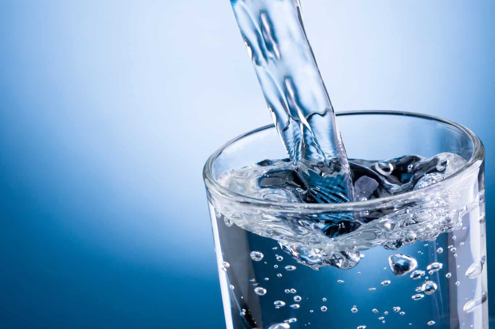 pouring-water-into-glass-on-blue-background