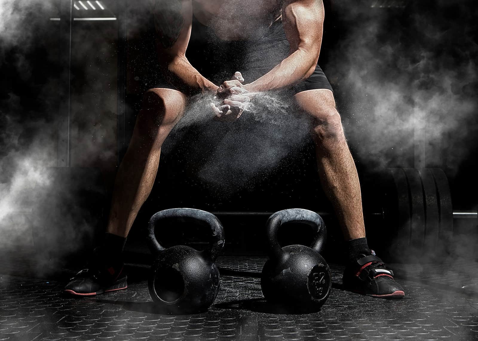 weightlifter-clapping-hands-and-preparing-for-workout-at-a-gym-focus-on-dust