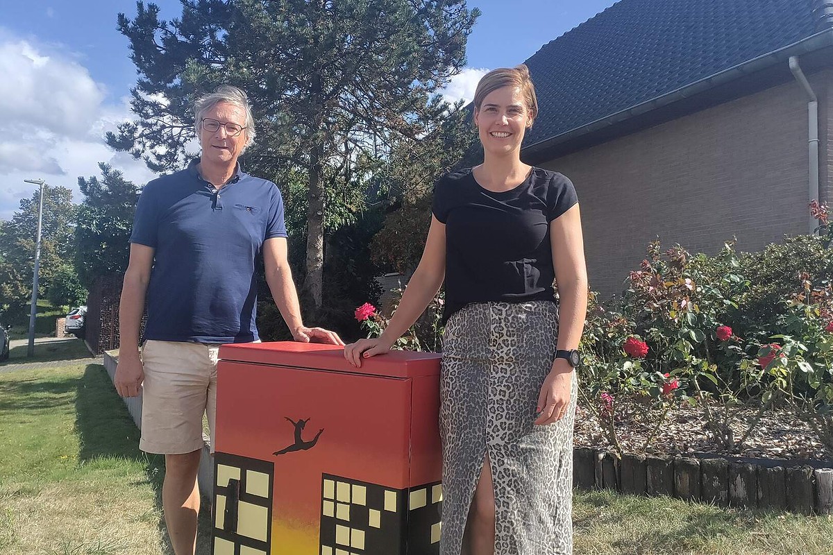 Burgemeester Ward Kennes en cultuurschepen Ellen Peeters staan bij de verfraaide nutskast Try to fly van kunstenaar Vesper Hackars in de Weverstraat in Kasterlee. © Gemeente Kasterlee