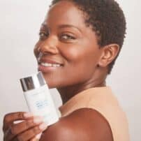 Colorescience® No-Show™ Mineral Sunscreen SPF 50 - dark skin model with bottle of product
