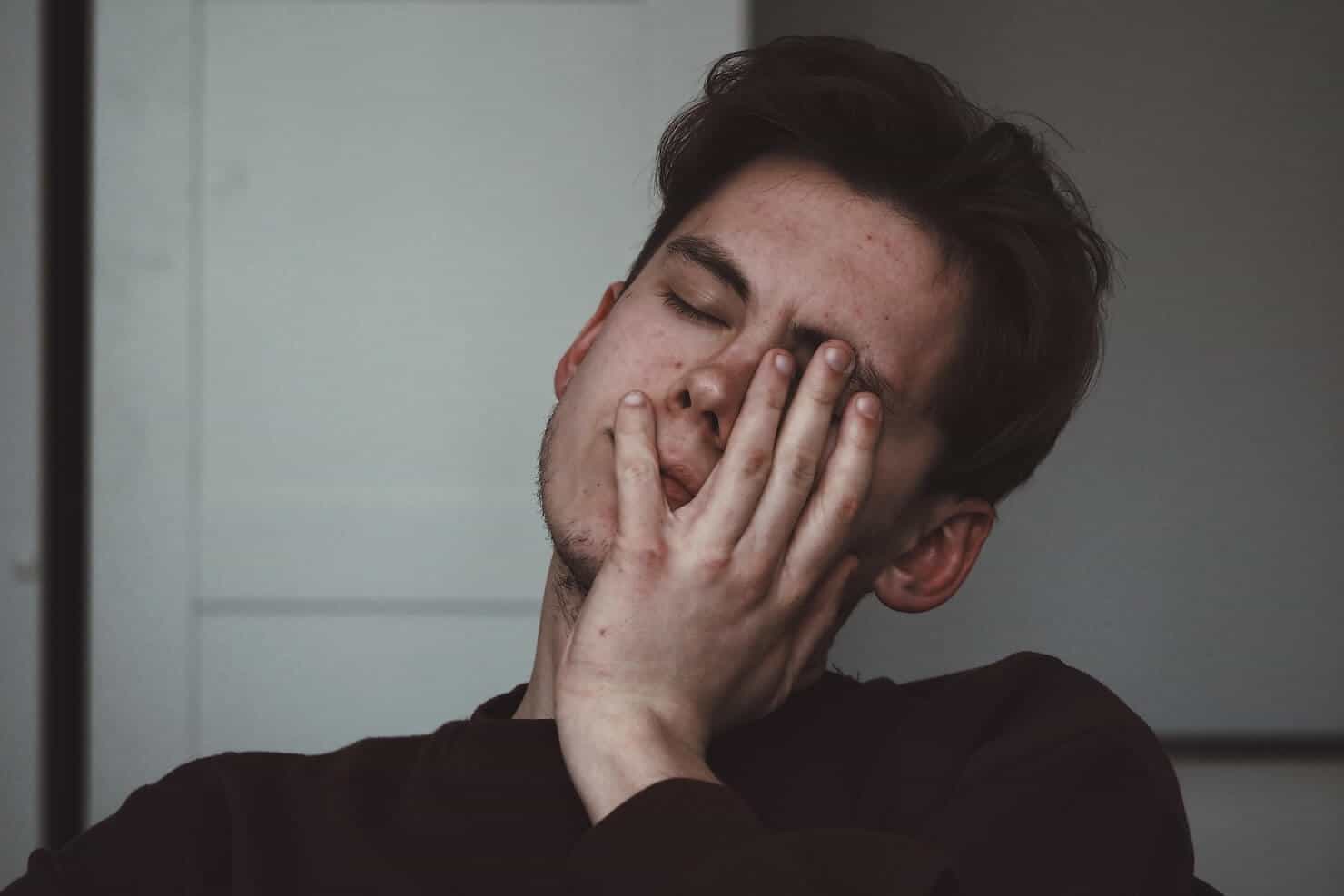 Male hand on face while stressed - prescription side effects for acne concept