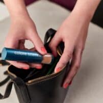Placing Sunforgettable brush on sunscreen in purse